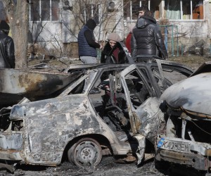 epa09791844 People walk past burned cars a day after a shelling on a residential area in Kiev, Ukraine, 28 February 2022. Russian troops entered Ukraine on 24 February prompting the country's president to declare martial law and triggering a series of severe economic sanctions imposed by Western countries on Russia.  EPA/SERGEY DOLZHENKO