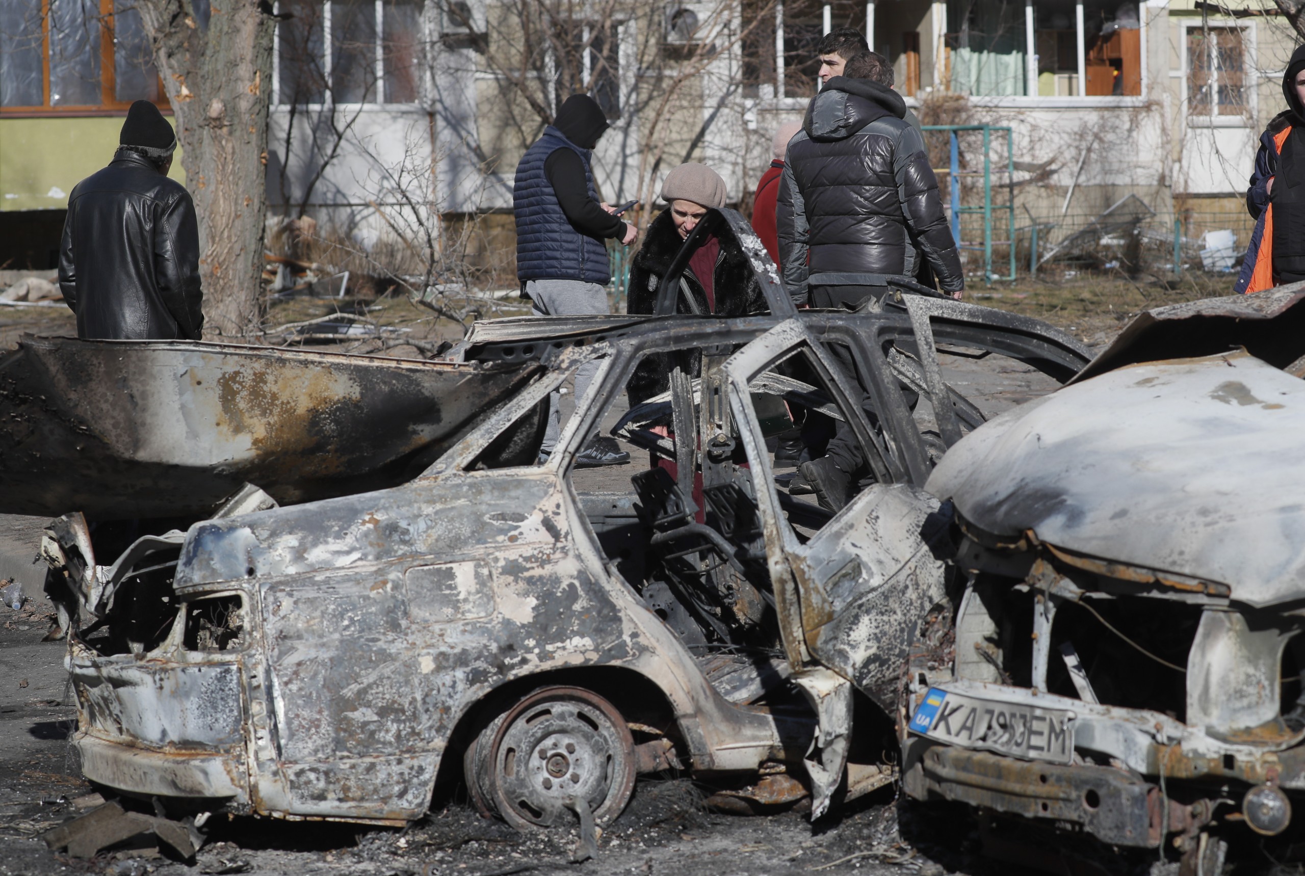 epa09791844 People walk past burned cars a day after a shelling on a residential area in Kiev, Ukraine, 28 February 2022. Russian troops entered Ukraine on 24 February prompting the country's president to declare martial law and triggering a series of severe economic sanctions imposed by Western countries on Russia.  EPA/SERGEY DOLZHENKO