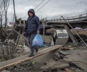 epa09806184 Civilians cross amid rubble of a damaged bridge in the Irpin city near from Kyiv (Kiev), Ukraine, 06 March 2022. Russian troops began a military operation in Ukraine on 24 February leading to a massive exodus of Ukrainians to neighboring countries as well as internal displacements.  EPA/OLEKSANDR RATUSHNIAK