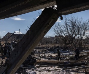 epa09815737 A police officer and a man carry on a destroyed bridge the dead body of a woman, who was allegedly killed by the Russian army, as residents flee from the frontline town of Irpin, Kyiv (Kiev) region, Ukraine, 10 March 2022. Thousands of residents are feeling Irpin and Bucha, as well as other settlements near Kyiv which were the most affected by the Russian army invasion.  EPA/ROMAN PILIPEY