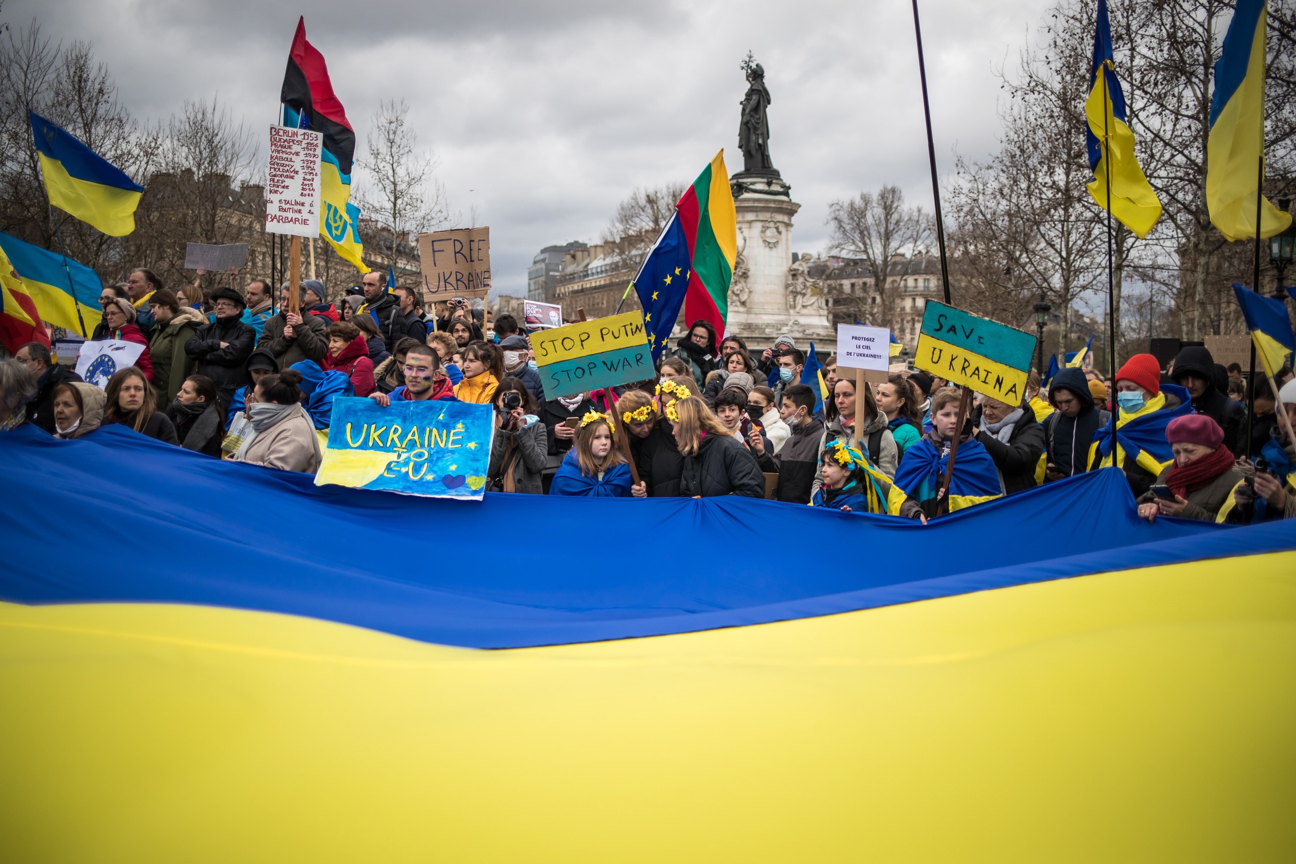 epa09819499 Protesters hold Ukrainian flags and posters as they take part in a demonstration against the Russian invasion of Ukraine, at Republique square in Paris, France, 12 March 2022. People all over the world hold vigils and demonstrations for peace in the Ukraine and against Russian troops invading the country.  EPA/CHRISTOPHE PETIT TESSON