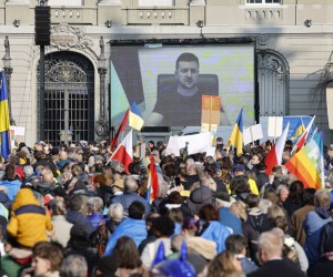 epa09835956 Ukrainian President Volodymyr Zelensky is displayed on a screen during a demonstration against the Russian invasion of Ukraine in front of the Swiss parliament building in Bern, Switzerland, 19 March 2022.  EPA/PETER KLAUNZER