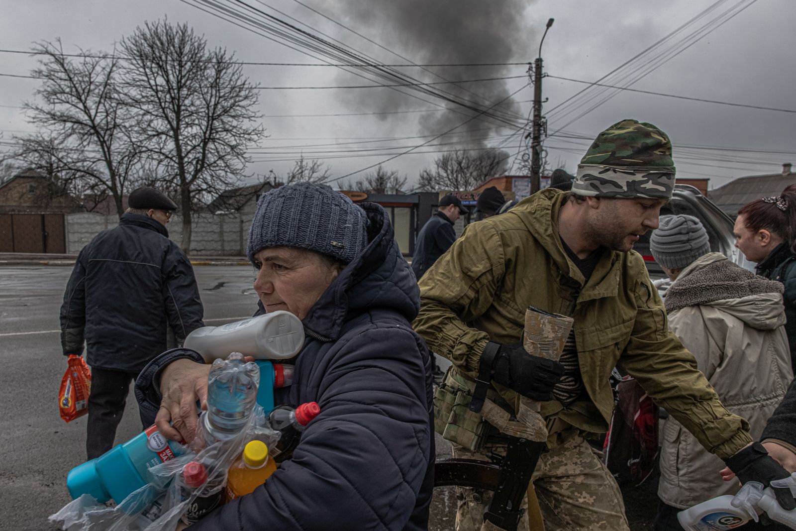 epa09840161 (FILE) - An elderly woman receives water and cleaning products distributed by Ukrainian military members to local residents as behind is seen smoke from a shelling, in Irpin city, Kyiv (Kiev) province, Ukraine, 03 March 2022 (reissued 21 March 2022). Since Russia invaded Ukraine one month ago on 24 February 2022, more than three million Ukrainians became refugees, around 700 civilians were killed and over 1.000 more injured, the United Nations said.  EPA/ROMAN PILIPEY  ATTENTION: This Image is part of a PHOTO SET