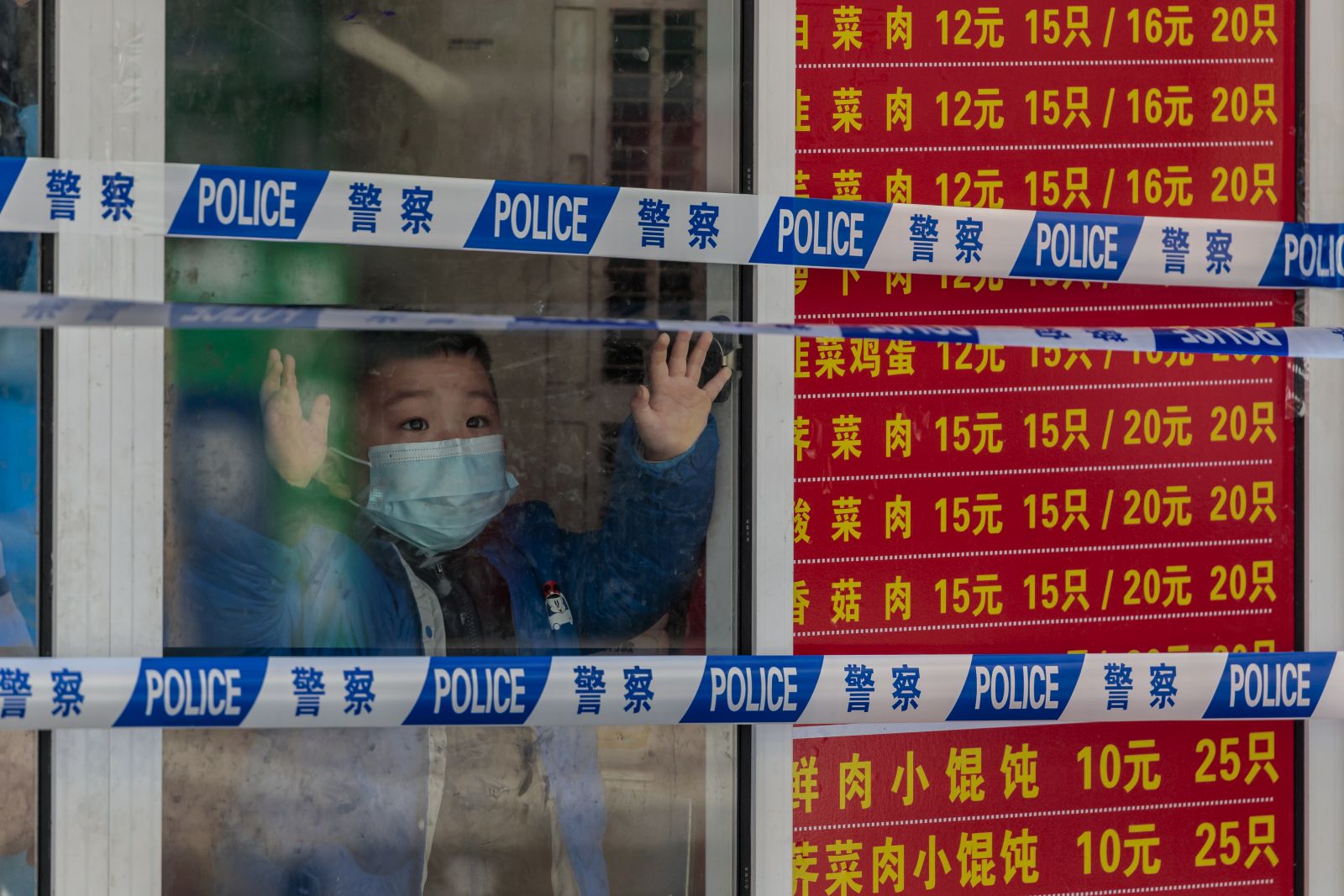 epa09857430 A quarantined boy looks through a shop window in a locked down restaurant, in Shanghai, China, 29 March 2022. On 29 March 2022, in China, there were 96 new locally transmitted COVID-19 cases and 4,381 asymptomatic infections, according to the National Health Commission. Shanghai city imposed a strict lockdown amid the COVID-19 resurgence. A complete lockdown hits the two biggest areas in the city, divided by the Huangpu River. East of the Huangpu River,  in the Pudong area the lockdown started on 28 March and lasts until 01 April, while in the western area, in Puxi, people will have a lockdown from 01 April to 05 April.  EPA/ALEX PLAVEVSKI