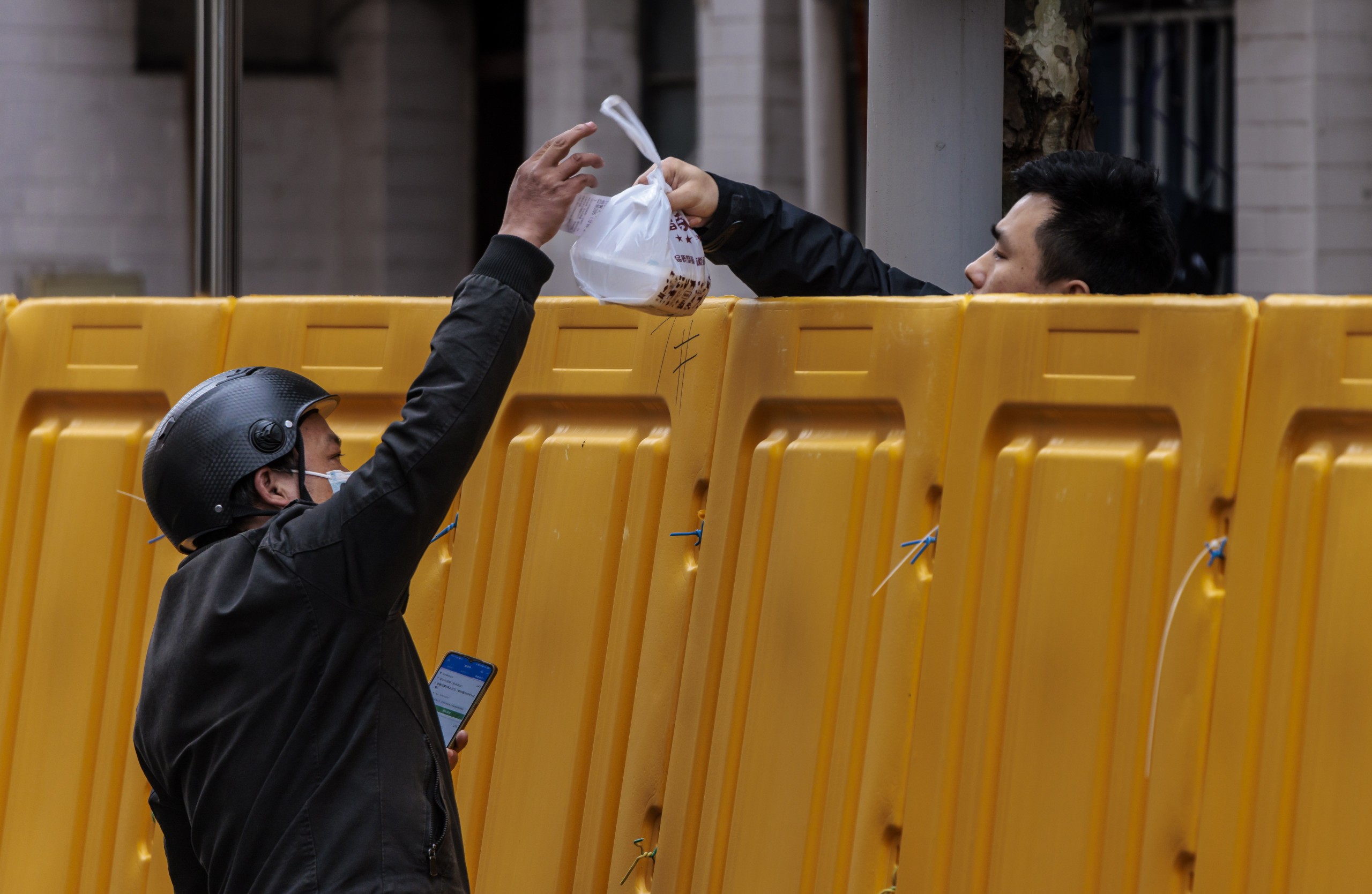 epa09861669 A man delivers food to a man in the compound under quarantine amid the lockdown, in Puxi side of the city, in Shanghai, China, 31 March 2022. Shanghai city imposed a strict lockdown amid the COVID-19 resurgence. A complete lockdown hits the two biggest areas in the city, divided by the Huangpu River. East of the Huangpu River, Pudong area, lockdown started on 28 March while west area, Puxi, will have a lockdown from 01 April.  EPA/ALEX PLAVEVSKI