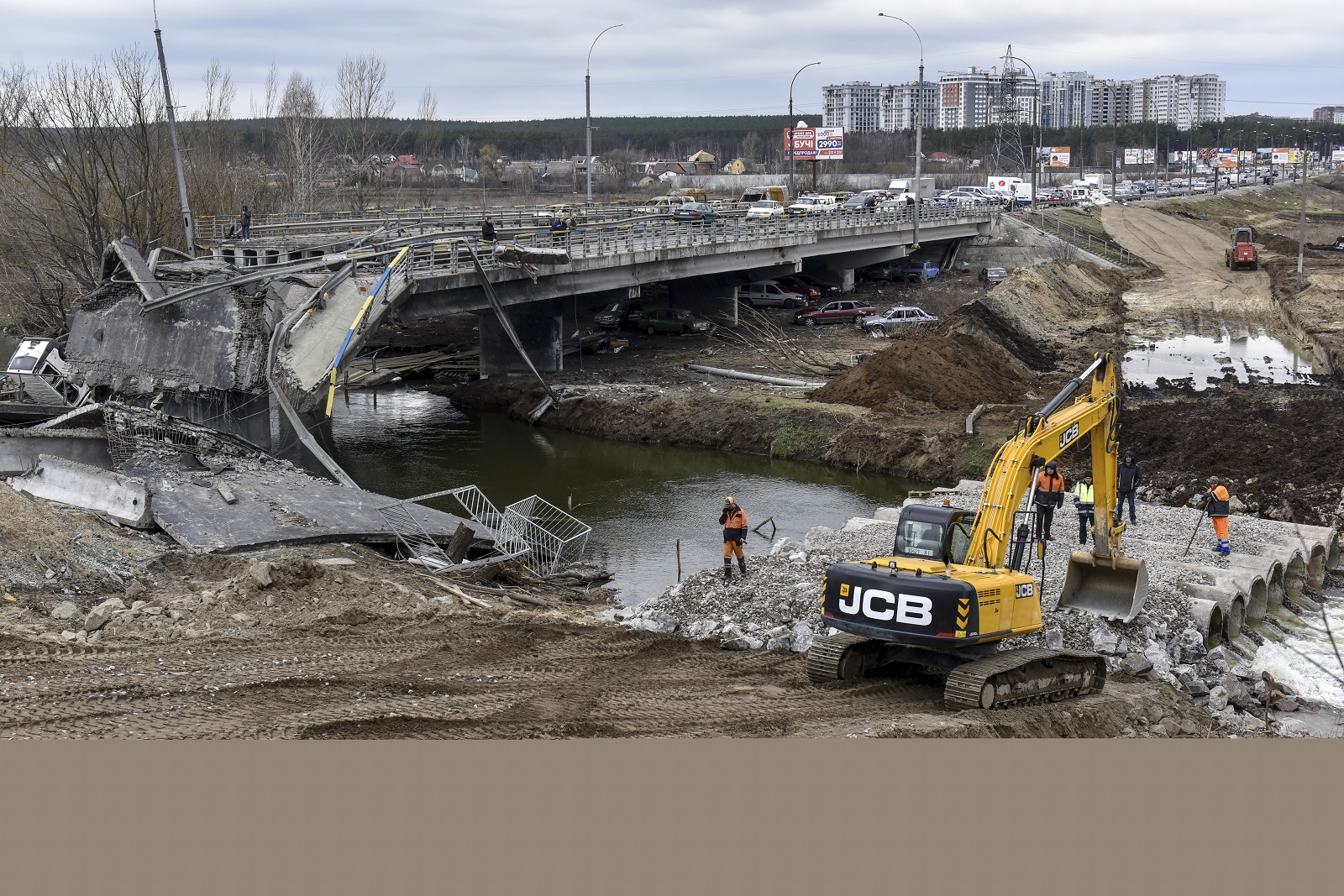 epa09873518 Ukrainians build a new bridge (R) over a river near the damaged old bridge (L) outside the recaptured city of Irpin, Ukraine, 06 April 2022. Ukrainian forces have recently recaptured from the Russian army some cities and villages in the outskirts of Kyiv.  EPA/OLEG PETRASYUK