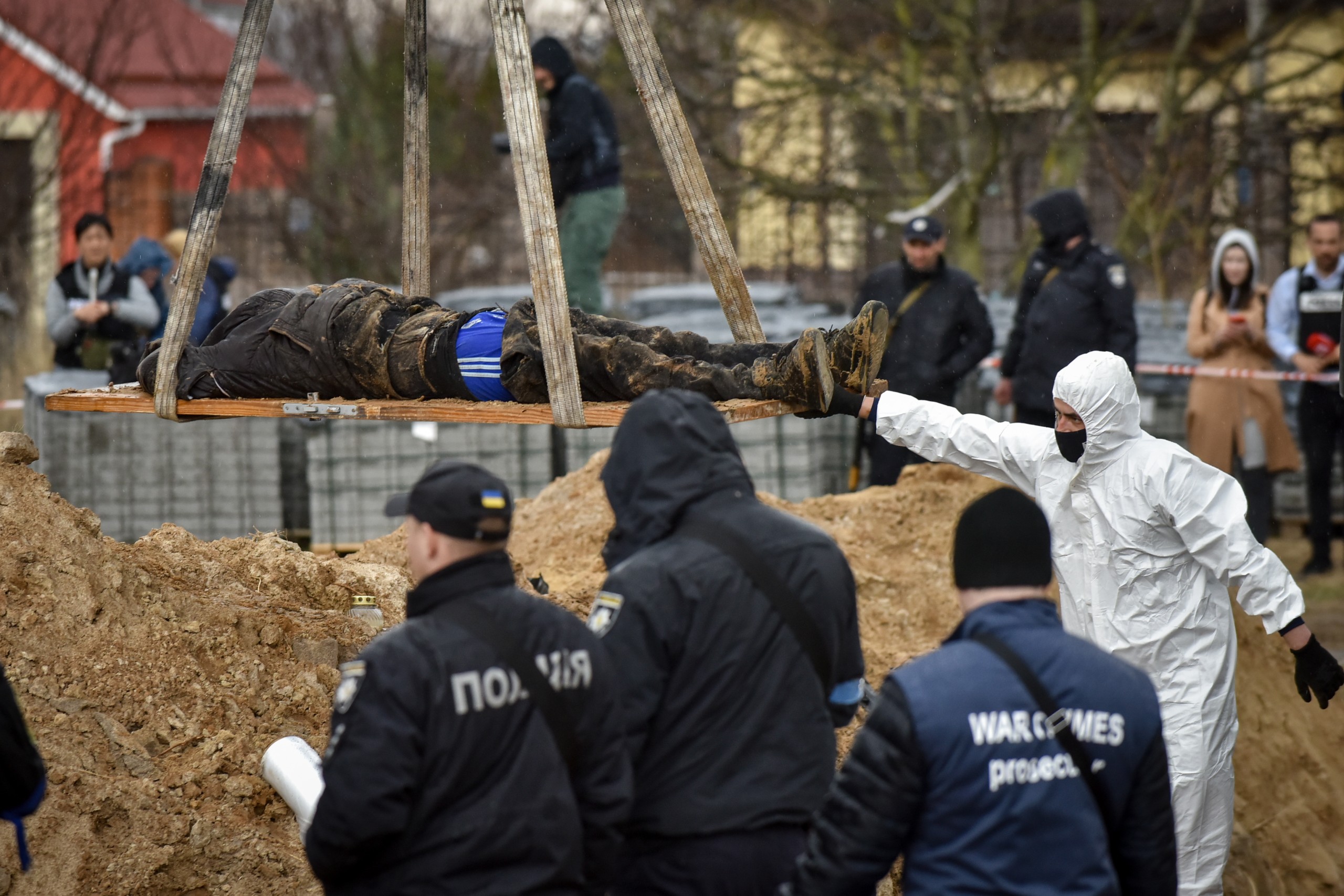 epa09878613 Police officers remove a body from a mass grave discovered in Bucha, outskirts of Kyiv (Kiev), Ukraine, 08 April 2022. Ukrainian authorities say that over 400 bodies were discovered following the Russian army’s retreat from towns surrounding Kyiv, prompting international calls for a probe into possible war crimes committed by Russia.  EPA/OLEG PETRASYUK
