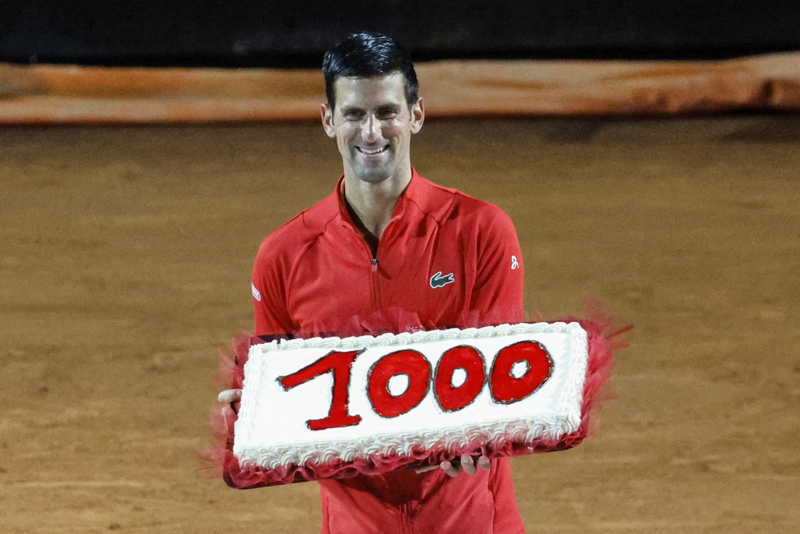 epa09947607 Serbia's Novak Djokovic holds a cake with the number of his 1,000th tour-level win earned after winning his men's singles semifinal match against Casper Ruud of Norway at the Italian Open tennis tournament in Rome, Italy, 14 May 2022.  EPA/FABIO FRUSTACI