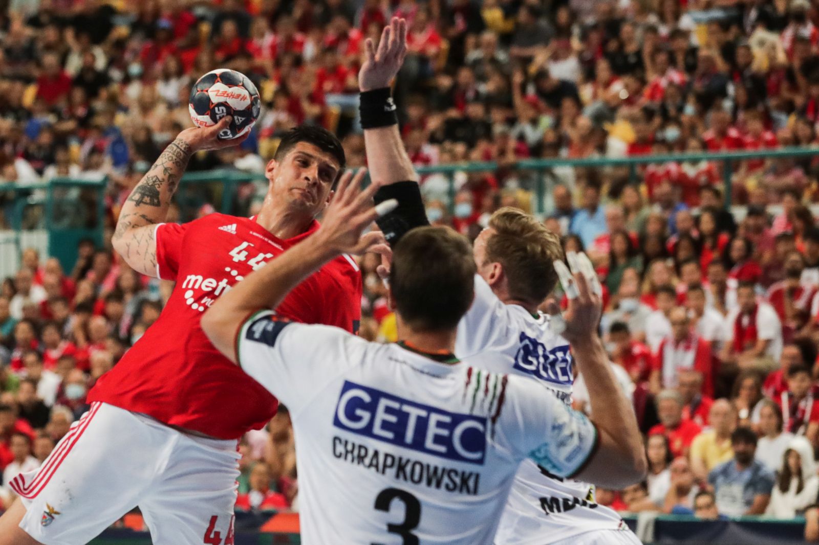 epa09985007 Benfica's Petar Djordjic (L) fights for the ball with Magdeburg's Piotr Chrapkowski (C) during the EHF European League final handball match SL Benfica vs SC Magdeburg at the Altice Arena in Lisbon, Portugal, 29 May 2022.  EPA/TIAGO PETINGA
