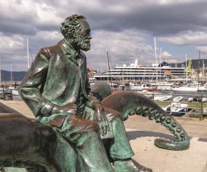 Vigo, Spain - Apr 25, 2020: Statue of french writer Jules Verne with a book sitting on an octopus in the port of Vigo