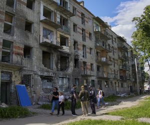 epa09974734 Locals walk past a residential building that was damaged during shelling in the outskirts of Kharkiv, Ukraine, 25 May 2022. Ukraine's second-largest city Kharkiv and its surroundings witnessed repeated airstrikes from Russian forces. On 24 February, Russian troops invaded Ukrainian territory starting a conflict that has provoked destruction and a humanitarian crisis. According to the UNHCR, more than 6.5 million refugees have fled Ukraine, and a further 7.7 million people have been displaced internally within Ukraine since.  EPA/SERGEY KOZLOV