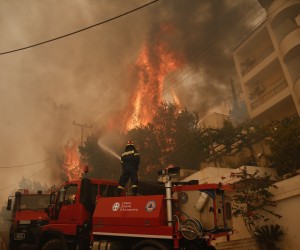 epa09995949 A fireman tries to extinguish flames during a wildfire in the suburb of Voula, south of Athens, Greece, 04 June 2022. Greek authorities ordered a limited evacuation in the coastal suburb of Voula, southern Athens, as strong winds fanning a raging fire have changed its direction, threatening residential area.  EPA/YANNIS KOLESIDIS