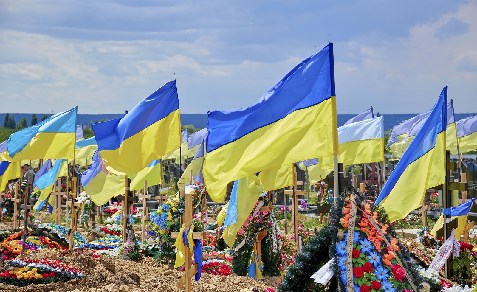 epa10013062 National flags rise above the graves of Ukrainian servicemen who died during more than three months of the Russian invasion at a cemetery in the Eastern Ukrainian city of Kharkiv, Ukraine, 14 June 2022. Russian troops on 24 February entered Ukrainian territory, starting a conflict that has provoked destruction and a humanitarian crisis.  EPA/SERGEY KOZLOV