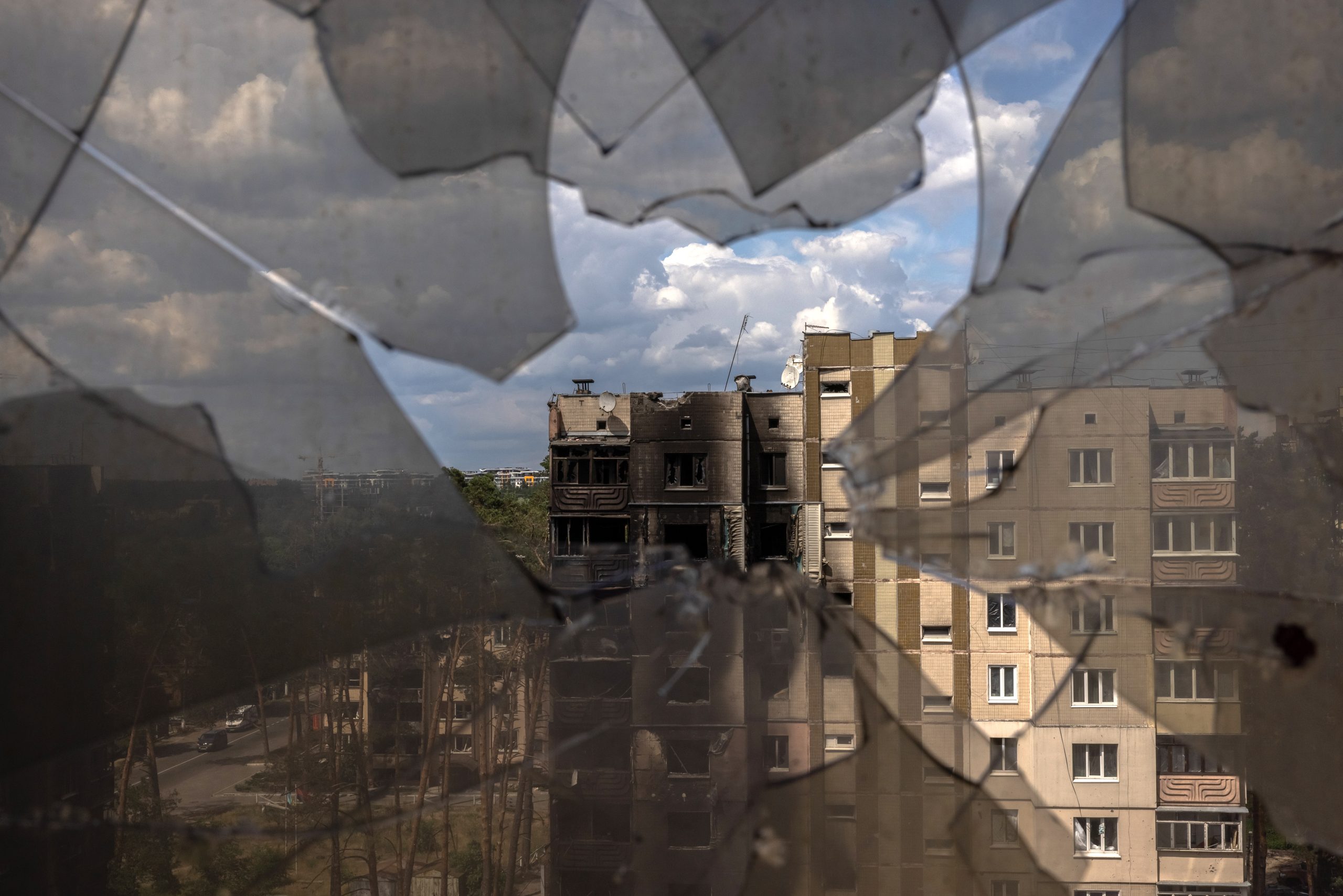 epa10016585 A look through broken window glass shows residential buildings damaged during Russian attacks in Irpin, Ukraine, 16 June 2022. The Ukrainian town of Irpin near Kyiv (Kiev), became a battlefield site when the Russian army attacked the Kyiv region in an attempt to reach Ukraine’s capital. Irpin was heavily shelled, causing death and destruction. At the end of March, when the town was taken back by the Ukrainian army, the mayor of Irpin announced that around 300 civilians and 50 Ukrainian servicemen were killed in Irpin during the Russian attacks. On 24 February Russian troops had invaded Ukraine resulting in fighting, deaths and destruction and a humanitarian crisis in the country.  EPA/ROMAN PILIPEY