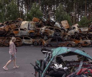 epa10016573 A woman walks past pile burned cars destroyed during Russian attacks in Irpin, Ukraine, 16 June 2022. The Ukrainian town of Irpin near Kyiv (Kiev), became a battlefield site when the Russian army attacked the Kyiv region in an attempt to reach Ukraine’s capital. Irpin was heavily shelled, causing death and destruction. At the end of March, when the town was taken back by the Ukrainian army, the mayor of Irpin announced that around 300 civilians and 50 Ukrainian servicemen were killed in Irpin during the Russian attacks. On 24 February Russian troops had invaded Ukraine resulting in fighting, deaths and destruction and a humanitarian crisis in the country.  EPA/ROMAN PILIPEY