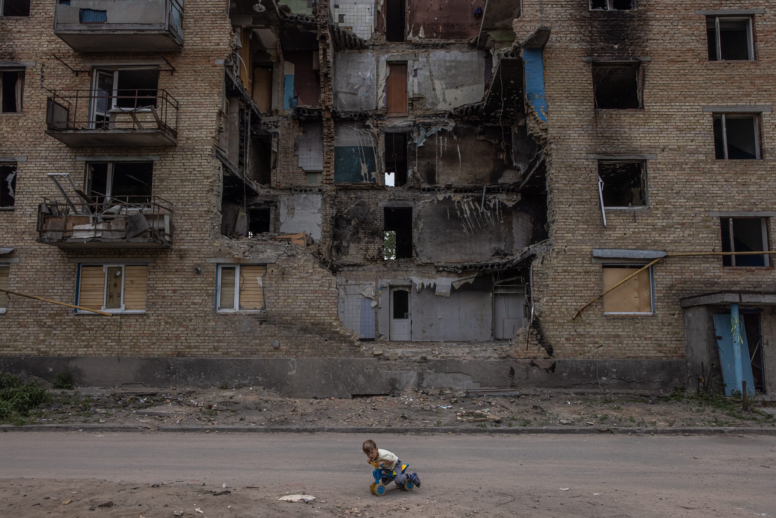 epa10018734 A child plays in front of a damaged residential building in Horenka, Kyiv (Kiev) region, Ukraine, 17 June 2022. Several towns and villages in the northern part of the Kyiv region became battlefields, heavily shelled, causing death and damage when Russian troops tried to reach the Ukrainian capital Kyiv in February and March 2022. Russian troops on 24 February entered Ukrainian territory, starting a conflict that has provoked destruction and a humanitarian crisis.  EPA/ROMAN PILIPEY