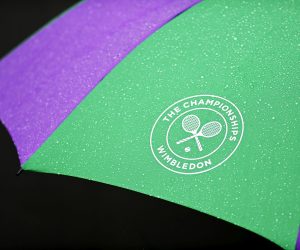 epa10036517 The Wimbledon logo on an umbrella is covered in rain as games are temporarily suspended due to rain on the first day at the Wimbledon Championships, in Wimbledon, Britain, 27 June 2022.  EPA/NEIL HALL   EDITORIAL USE ONLY