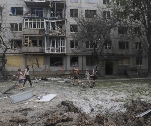 epa10011224 Locals walk past a residential building damaged in recent shelling in the city of Bakhmut, Donetsk region, eastern Ukraine, 13 June 2022, amid the Russian invasion. Russian troops on 24 February entered Ukrainian territory, starting a conflict that has provoked destruction and a humanitarian crisis.  EPA/STRINGER