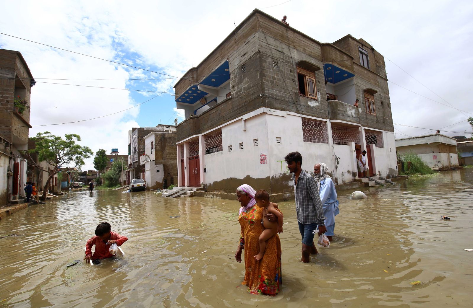 epa10065075 People make their way through a flooded area after heavy monsoon rains in Karachi, Pakistan, 11 July 2022. Heavy rains have claimed 77 lives so far in Pakistan during the current monsoon season that started on June 14, according to Sherry Rehman, Federal Minister for Climate Change. Heavy rains have lashed multiple parts of the country, with Balochistan being the most severely affected, with 274 percent more precipitation than the average, while in Sindh it was 261 percent, according to the minister.  EPA/SHAHZAIB AKBER