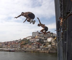 epa10067321 Boys jump from the Dom Luiz Bridge into the Douro River to cool off during a hot day in Porto, Portugal, 12 July 2022. The high temperatures of recent days should worsen until the end of the week in mainland Portugal, with thermometers exceeding 40°C in many districts.  EPA/JOSE COELHO
