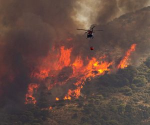 epa10072820 A helicopter pours water into the flames of a forest fire in Mijas, Malaga, southern Spain, 15 July 2022. Regional authorities activated the first level of the Emergency Plan for Forest Fire Emergencies as the fire has been spreading since noon and some residential areas have already been evacuated.  EPA/DANIEL PEREZ