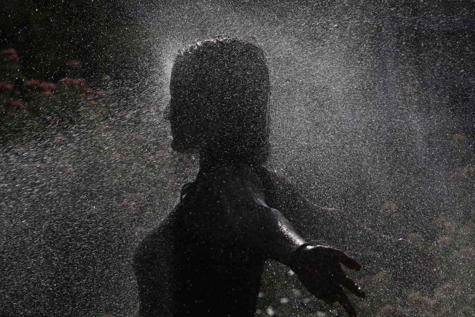 epa10074219 A woman cools off under sprinkrels in Cordoba, in Andalusia, Spain, 16 July 2022. Spanish state weather agency issued a red alert in five different communities -Aragon, Cantabria, Extremadura, Navarra and La Rioja- with temperatues reaching up to 44 degrees.  EPA/SALAS
