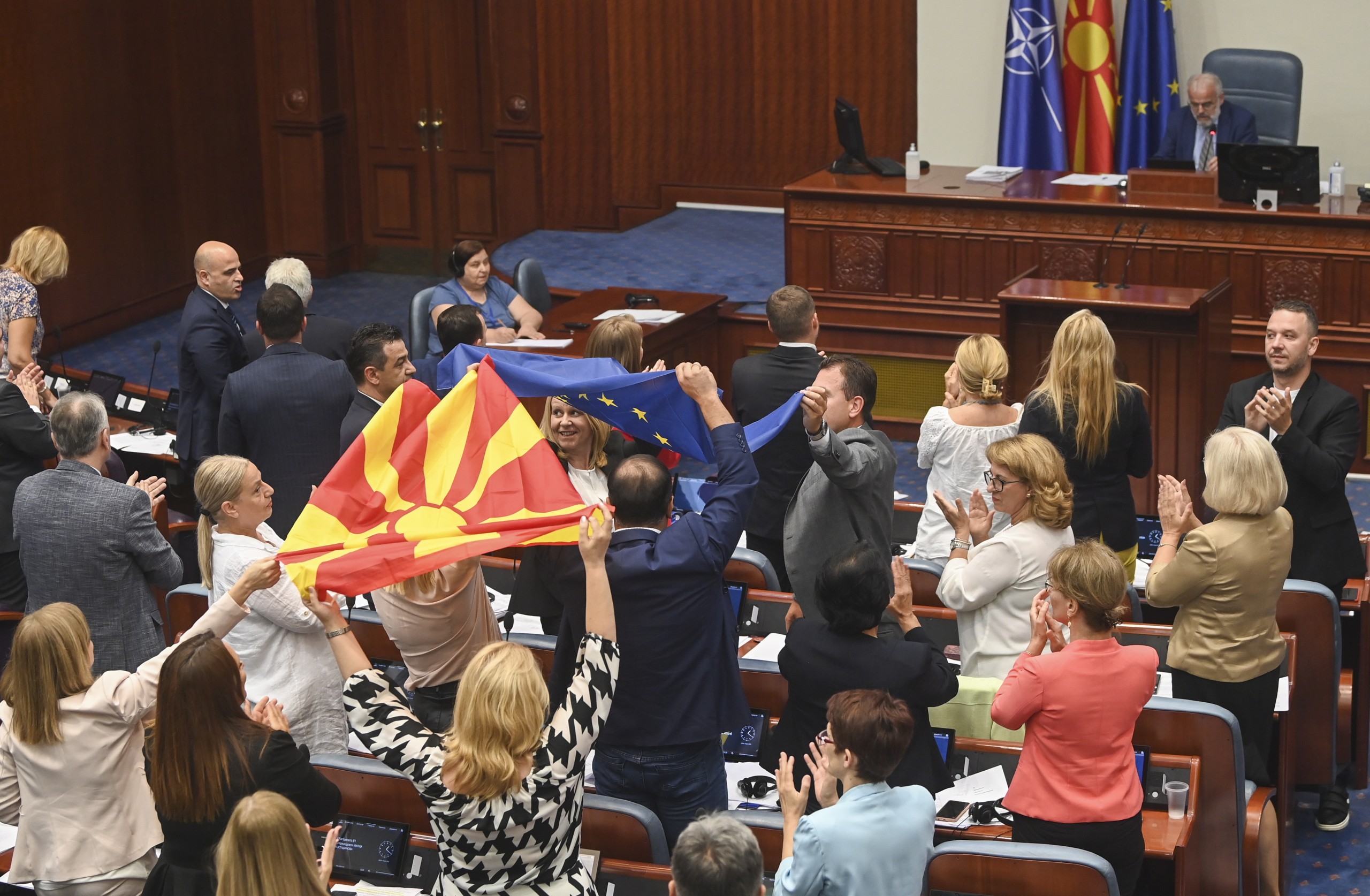 epa10074236 Lawmakers wave Macedonian and EU flags after voting in the Parliament building in Skopje, Republic of North Macedonia, 16 July 2022. The Parliament of North Macedonia voted the conclusions authorizing the Government to accept the EU accession Negotiation Framework proposed by the French Presidency with the Council of EU.  EPA/GEORGI LICOVSKI