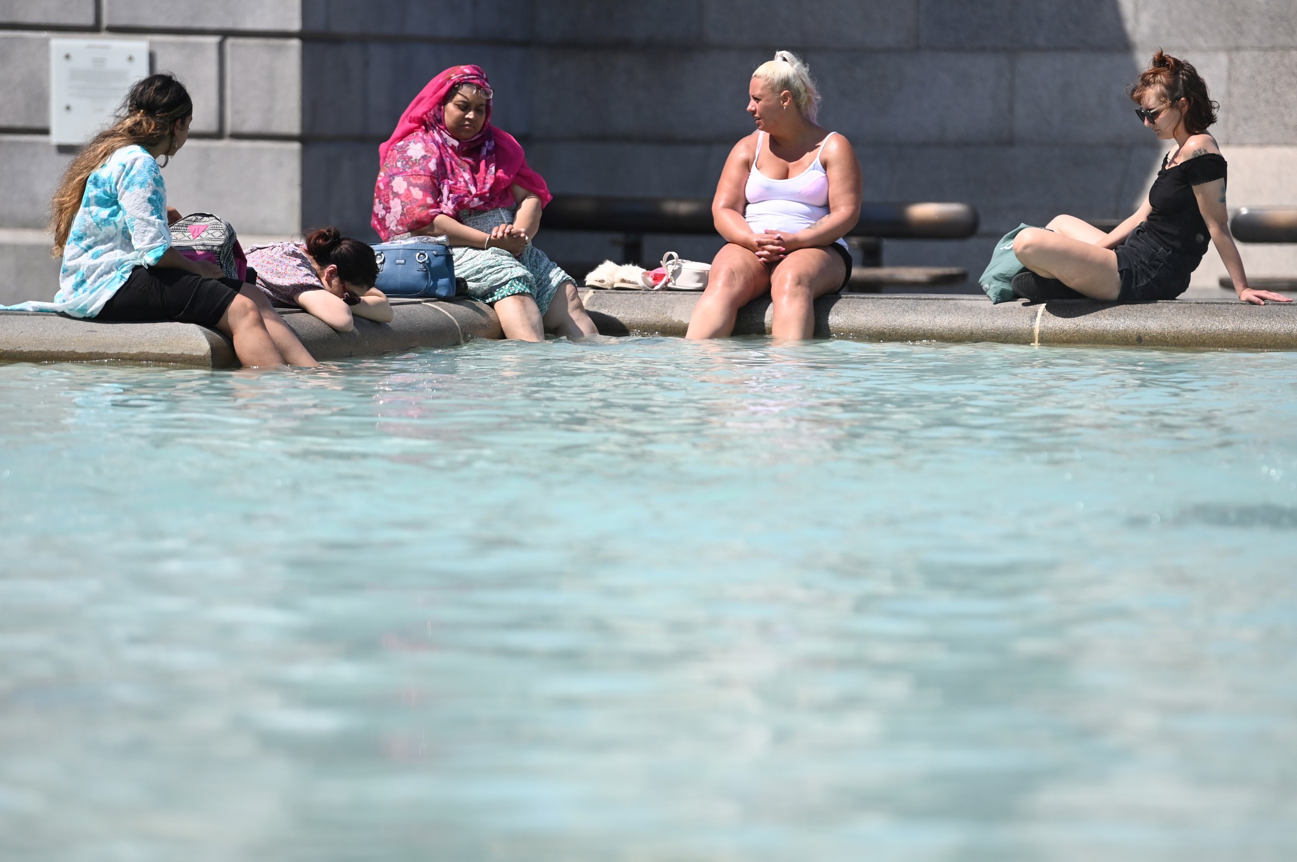 epa10079932 People cool themselves in a fountain at Trafalgar Square in London, Britain, 19 July 2022. The Met Office has issued a red extreme heat warning as the UK could have its hottest day on record this week, with temperatures forecast to hit up to 41 Celsius.  EPA/NEIL HALL