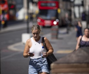 epa10079936 A woman drinks water whilst walking across London Bridge on a hot day in London, Britain, 19 July 2022. Britain is suffering from extreme hot weather as the temperatures in London reached 40.2C, the highest ever on record, according to Met Office figures. Transport for London (TfL) warned commuters not to travel on public transport as the infrastructure are under increased pressure with the unprecedented temperatures.  EPA/TOLGA AKMEN