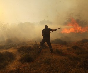 epa10080172 A firefighter battles a wildfire raging in Ntaou village, Penteli, Greece, 19 July 2022. Ninteen fire engines crewed by 50 firefighters, 5 water-dropping helicopters and 11 5 water-dropping airplanes were out battling the blaze, while strong winds are blowing at the spot.  EPA/GEORGE VITSARAS