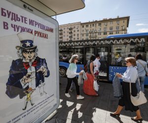 epa10082476 Russian people walk at a bus stop near a poster (L) depicting Uncle Sam, a personification of the federal government of the United States, reading 'Don't be a toy in the wrong hands' in Moscow, Russia,in Moscow, Russia, 20 July 2022. On 24 February 2022 Russian troops entered the Ukrainian territory in what the Russian president declared a 'Special Military Operation', starting an armed conflict that has provoked destruction and a humanitarian crisis.  EPA/YURI KOCHETKOV