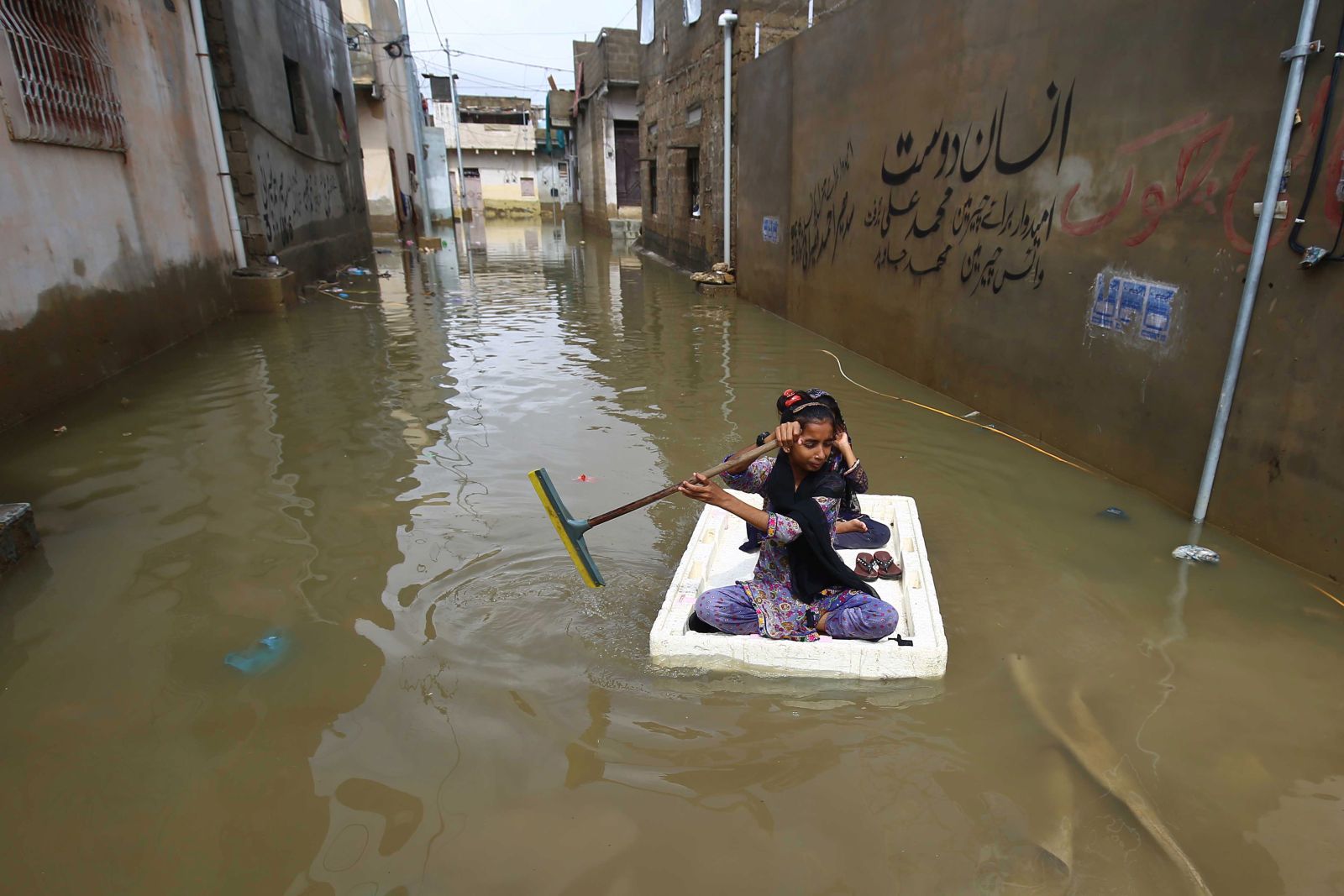 epa10092118 Children make their way through a flooded area after heavy monsoon rains in Karachi, Pakistan, 26 July 2022. Heavy rains have claimed 304 lives so far in Pakistan during the current monsoon season.  EPA/SHAHZAIB AKBER