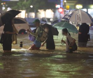 epa10112000 People wade though an inundated road in southern Seoul, South Korea, 08 August 2022 (issued 09 August 2022), as heavy rainfall of over 100 millimeters per hour, the heaviest in 80 years, battered Seoul and surrounding areas.  EPA/YONHAP SOUTH KOREA OUT