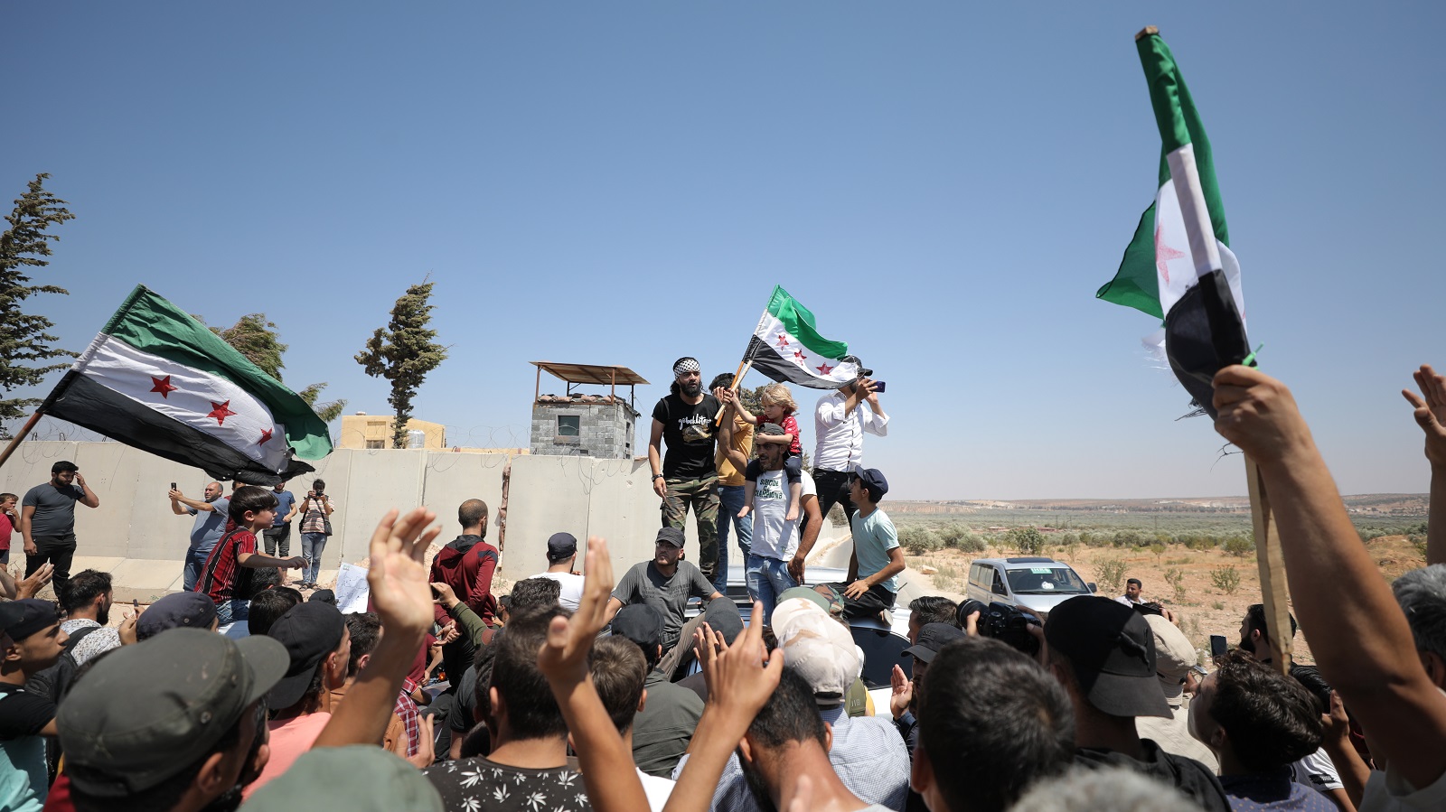 epa10117197 Syrian people protest near a Turkish military post against Turkish calls for reconciliation between rebels and the Syrian government, in Al-Mastumah village, seven kilometers south of Idlib, Syria, 12 August 2022. Protests erupted in cities in northern Syria that are held by Syrian opposition groups a day after Turkish Foreign Minister Mevlut Cavusoglu's statements on possible reconciliation between the Syrian opposition and government.  EPA/YAHYA NEMAH