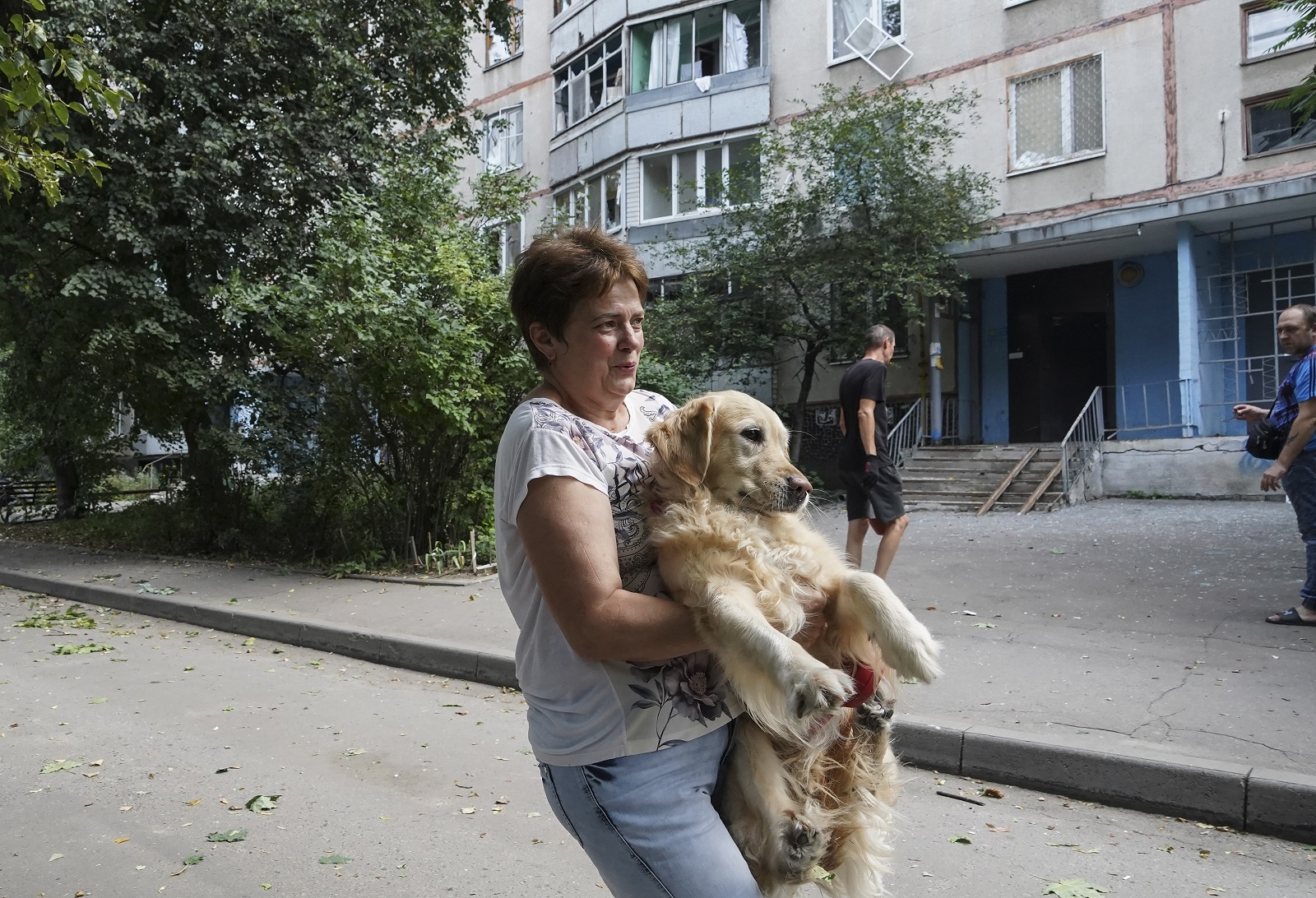 epa10122499 A local woman carries her dog to save its paws from fragments of broken glass after a shelling of a residential building in Kharkiv, Ukraine, 15 August 2022 amid Russia's military invasion. Five people were injured in a result of the shelling, the Ukrainian Rescue Service has reported. Kharkiv and surrounding areas have been the target of heavy shelling since February 2022, when Russian troops entered Ukraine starting a conflict that has provoked destruction and a humanitarian crisis.  EPA/VASILIY ZHLOBSKY