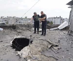 epa10122497 Ukrainian rescuers inspect a shelling hole on the roof of a residential building after a shelling in Kharkiv, Ukraine, 15 August 2022 amid Russia's military invasion. Five people were injured in a result of the shelling, the Ukrainian Rescue Service has reported. Kharkiv and surrounding areas have been the target of heavy shelling since February 2022, when Russian troops entered Ukraine starting a conflict that has provoked destruction and a humanitarian crisis.  EPA/VASILIY ZHLOBSKY