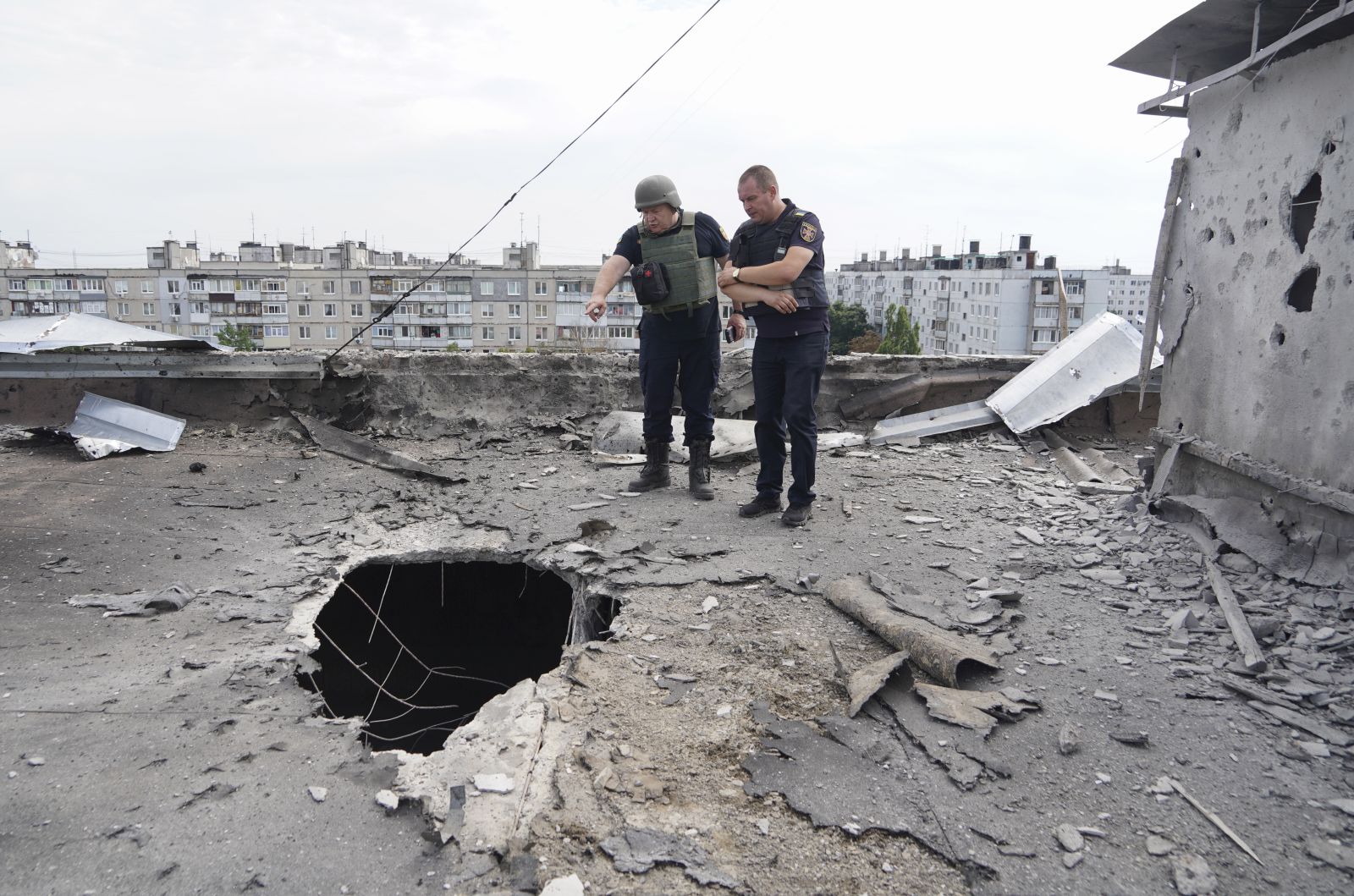 epa10122497 Ukrainian rescuers inspect a shelling hole on the roof of a residential building after a shelling in Kharkiv, Ukraine, 15 August 2022 amid Russia's military invasion. Five people were injured in a result of the shelling, the Ukrainian Rescue Service has reported. Kharkiv and surrounding areas have been the target of heavy shelling since February 2022, when Russian troops entered Ukraine starting a conflict that has provoked destruction and a humanitarian crisis.  EPA/VASILIY ZHLOBSKY