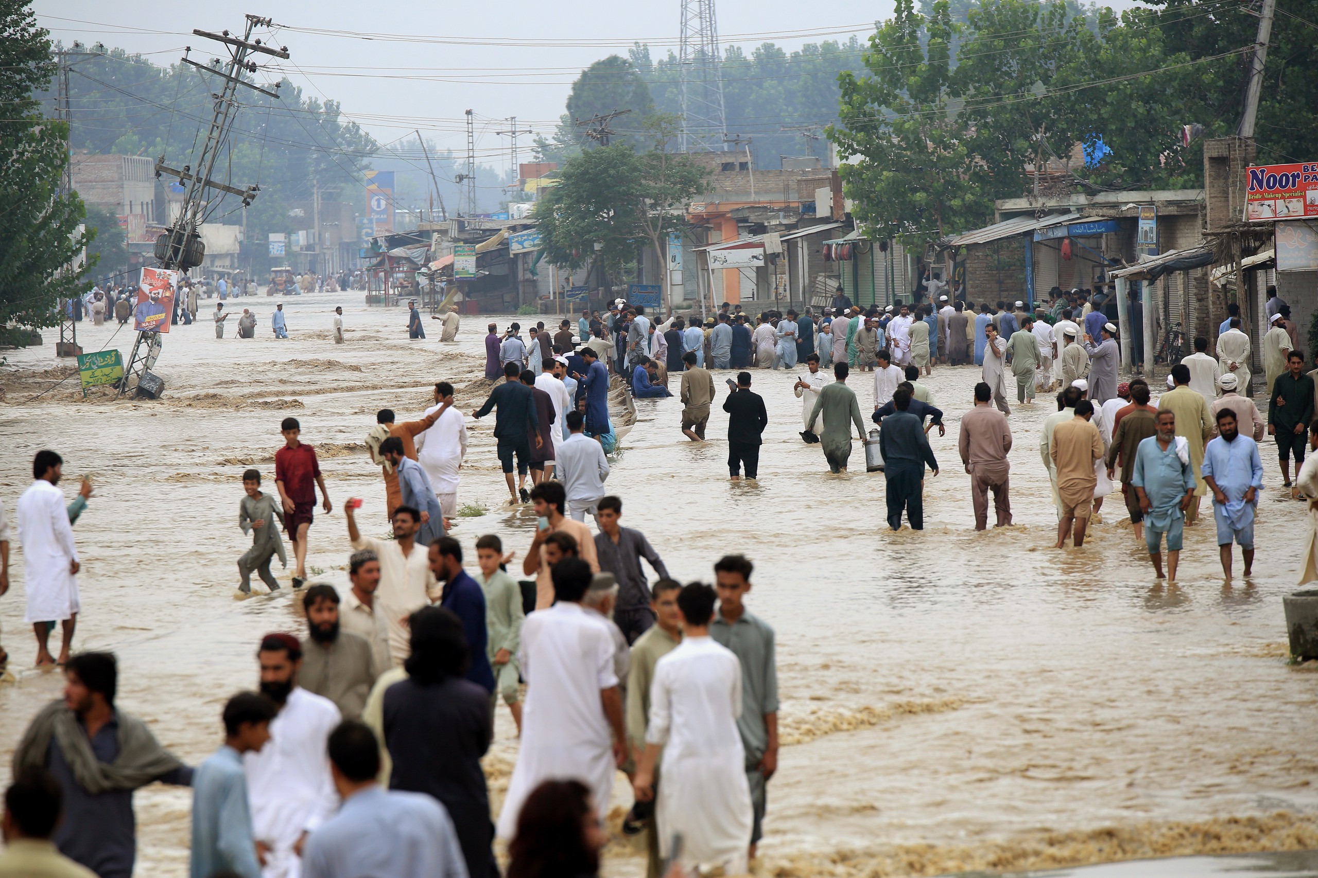 epaselect epa10141286 People wade through a flooded area following heavy rains in Charsadda District, Khyber Pakhtunkhwa province, Pakistan, 27 August 2022. According to the National Disaster Management Authority (NDMA) on 26 August, flash floods triggered by heavy monsoon rains have killed over 900 people across Pakistan since mid-June 2022. More than 33 million people have been affected by floods, the country's climate change minister said.  EPA/ARSHAD ARBAB