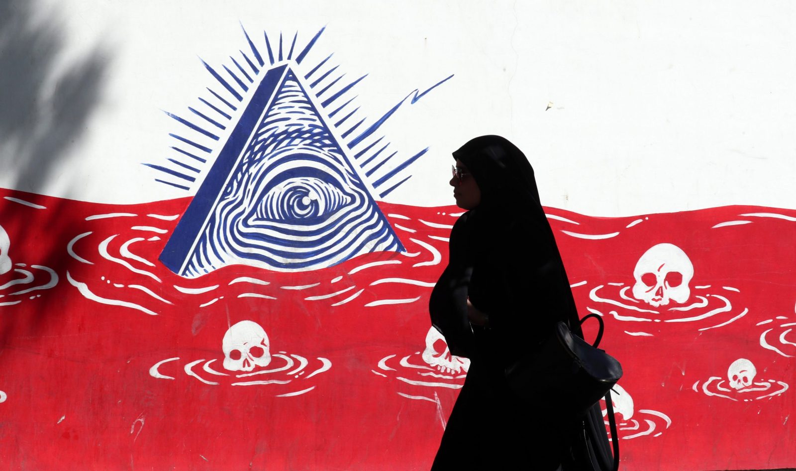 epa10160875 A silhouetted Iranian woman walks past an anti-US wall painting on the wall of former US embassy in the capital city of Tehran, Iran, 05 September 2022. Following the indirect exchange of responses through the EU representative between Iran and the United States regarding nuclear deal, Iran is now waiting for the US response to its latest nuclear proposal. Iran and the US has been exchanging their nuclear deal proposals indirectly through the EU, aimed at salvaging the 2015 nuclear deal with world powers. US says that will announce its answer to Iran's nuclear deal proposal in-time after reviewing all the aspects. One of the main Iran's demands is that all the sanctions against the country should be remove. Iran is facing economic crisis over sanctions by US and EU.  EPA/ABEDIN TAHERKENAREH