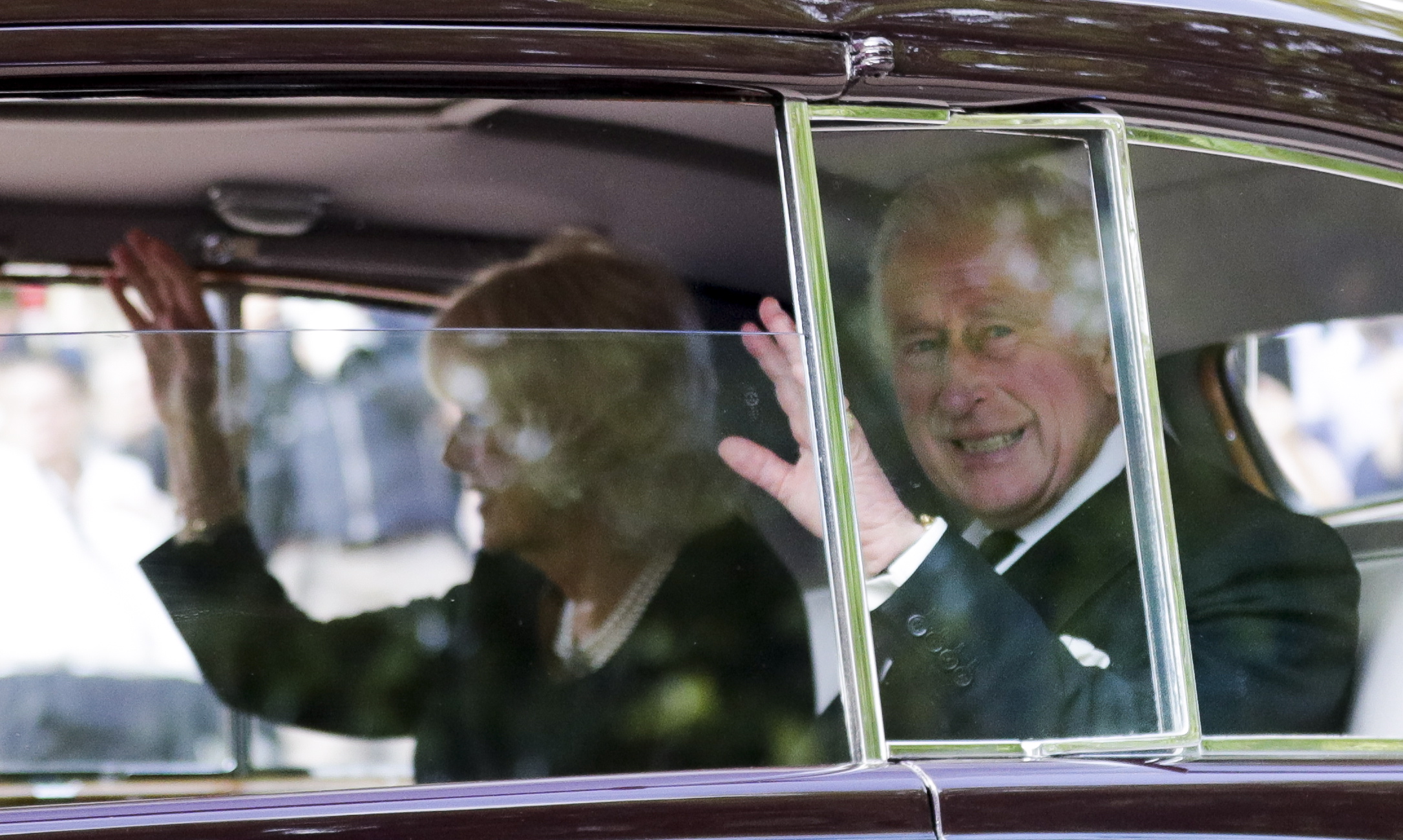 epa10179455 Britain's King Charles III and Camilla, the Queen Consort, gesture as they are driven on the way to Westminster, in London, Britain, 12 September 2022. King Charles III will address Parliament for the first time as monarch on 12 September. King Charles III was announced as the new sovereign during a meeting of the Accession Council on 10 September following the death of Britain's Queen Elizabeth II at her Scottish estate on 08 September.  EPA/OLIVIER HOSLET