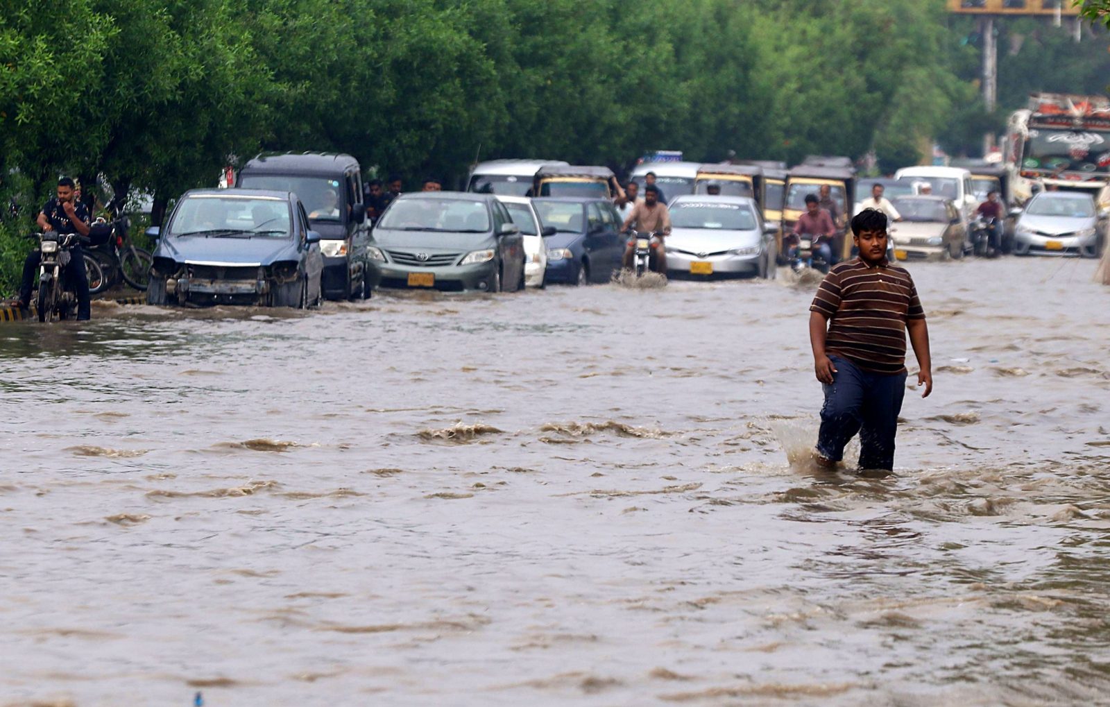 epa10181582 People make their way through a flooded area following heavy rains in Karachi, Sindh province, Pakistan, 13 September 2022. According ?to disaster management authorites, around 160 bridges and 5,000 km (3,200 miles) of roads have been destroyed or damaged, 3.5 million acres of crops af?fected and about 800,000 livestock lost. Flash floods triggered by heavy monsoon rains have killed over 1,200 people across Pakistan since mid-June 20?22. More than 33 million people have been affected by floods, the country's climate change minister Sherry Rehman said.  EPA/SHAHZAIB AKBER