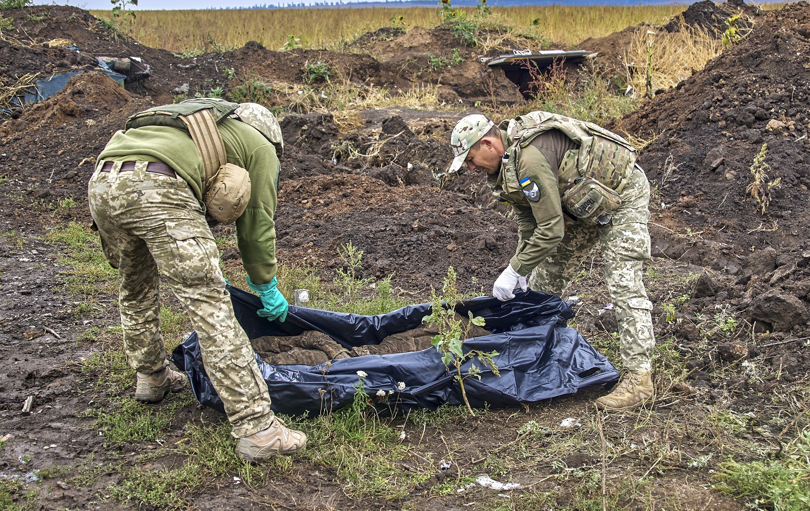 epa10188478 Ukrainian soldiers, members of a special evacuation team, exhume the body of a Ukrainian National Guard soldier who was killed in fighting in the first days of Russia's invasion, near the urban settlement Kazachya Lopan, north of Kharkiv, northeastern Ukraine, 16 September 2022. The Ukrainian army pushed Russian troops from occupied territory in the northeast of the country in a counterattack. Kharkiv and surrounding areas have been the target of heavy shelling since February 2022, when Russian troops entered Ukraine starting a conflict that has provoked destruction and a humanitarian crisis.  EPA/SERGEY KOZLOV -- ATTENTION EDITORS: GRAPHIC CONTENT