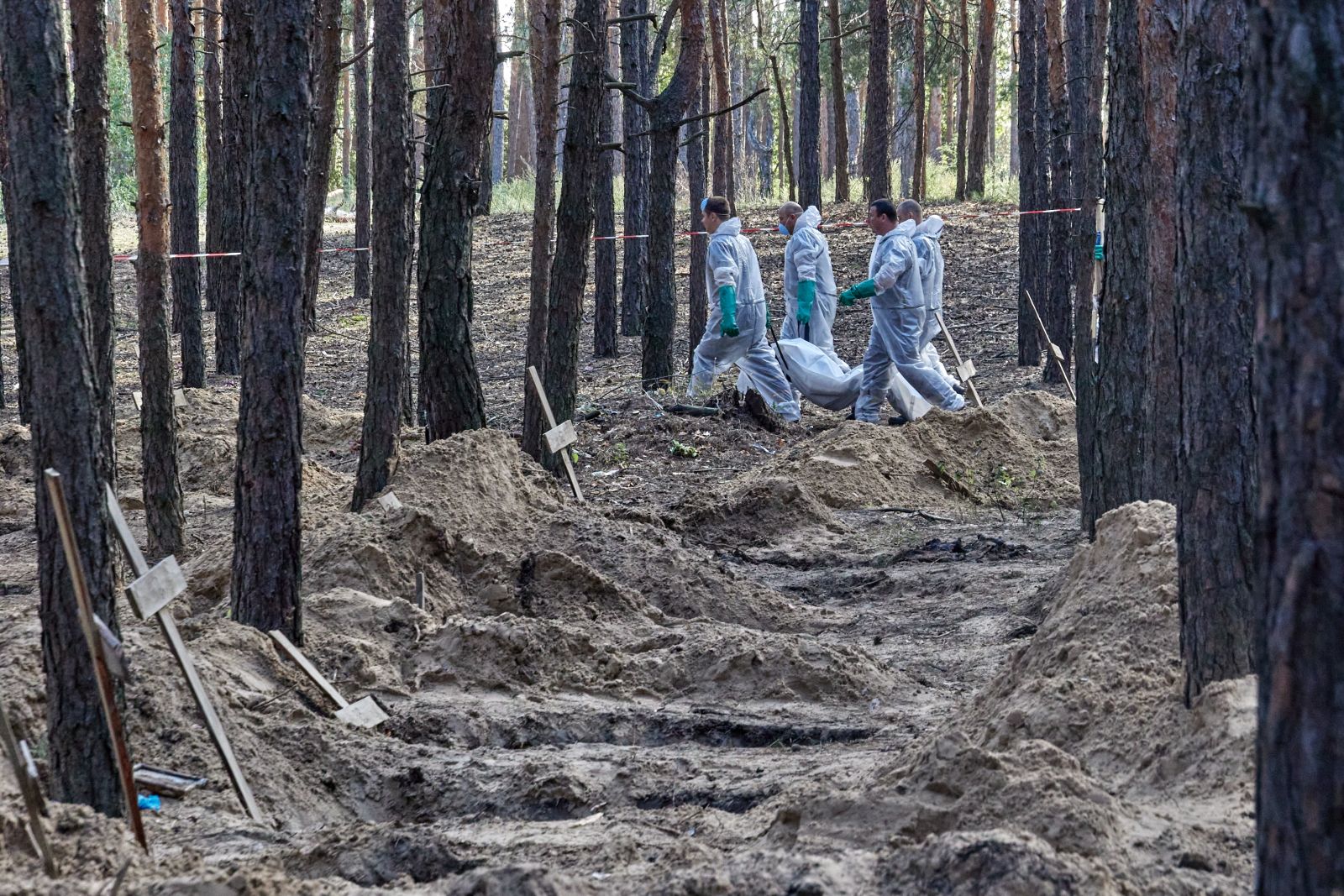 epa10194312 Ukrainian workers carry a body that was unearthed from graves in Izyum, Kharkiv region, northeastern Ukraine, 19 September 2022. A mass burial site was found after Ukrainian troops recaptured the town of Izyum. According to the head of the investigative department of the police of the Kharkiv region, the burial site, one of the largest in a recaptured city so far, counts more than 440 separate graves. The Ukrainian army pushed Russian troops from occupied territory in the northeast of the country in a counterattack. Kharkiv and surrounding areas have been the target of heavy shelling since February 2022, when Russian troops entered Ukraine starting a conflict that has provoked destruction and a humanitarian crisis.  EPA/SERGEY KOZLOV