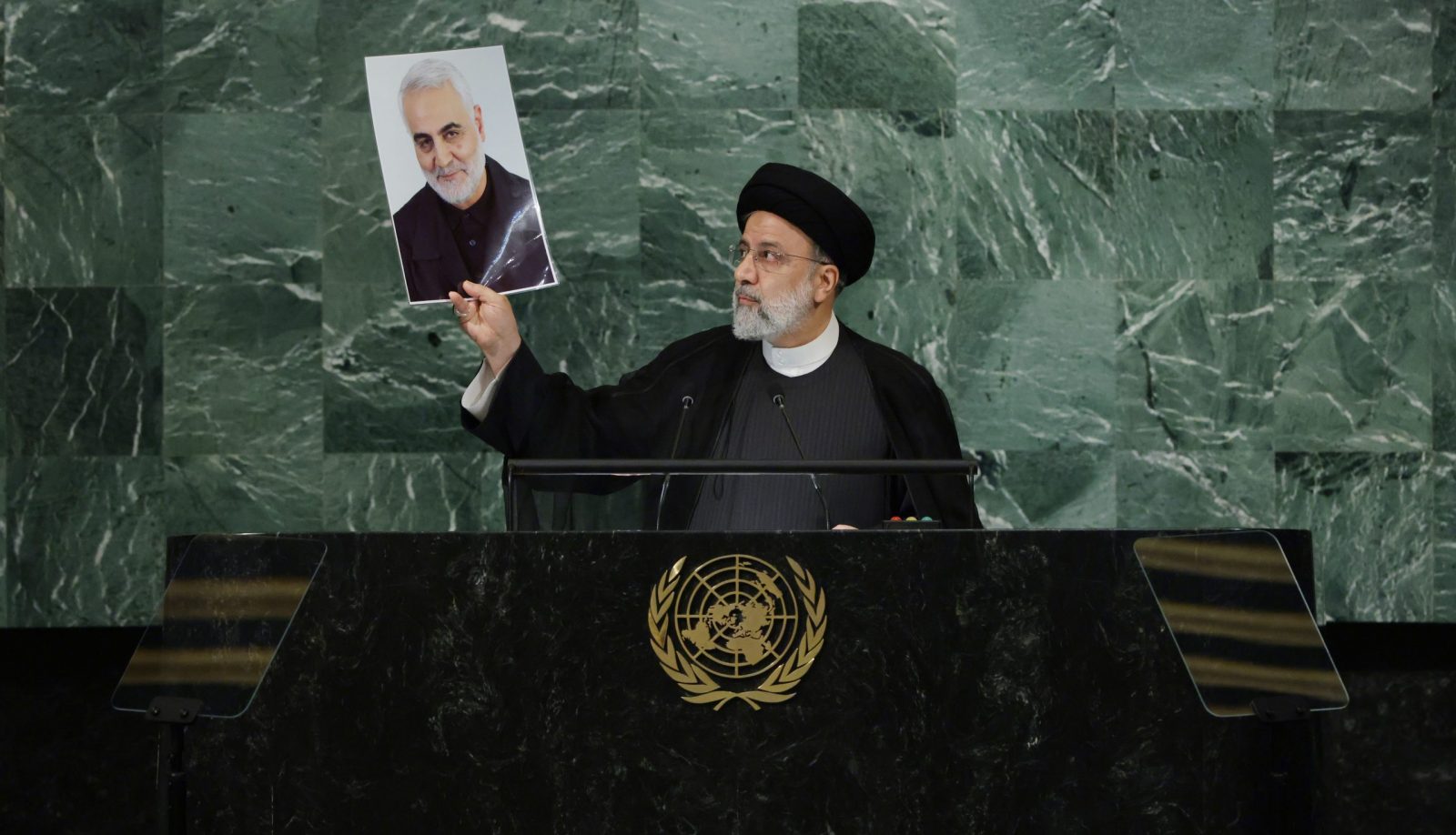 epa10196878 President Seyyed Ebrahim Raisi of Iran holds up a photo of Qasem Soleimani as he delivers his address during the 77th General Debate inside the General Assembly Hall at United Nations Headquarters in New York, New York, USA, 21 September 2022.  EPA/JUSTIN LANE