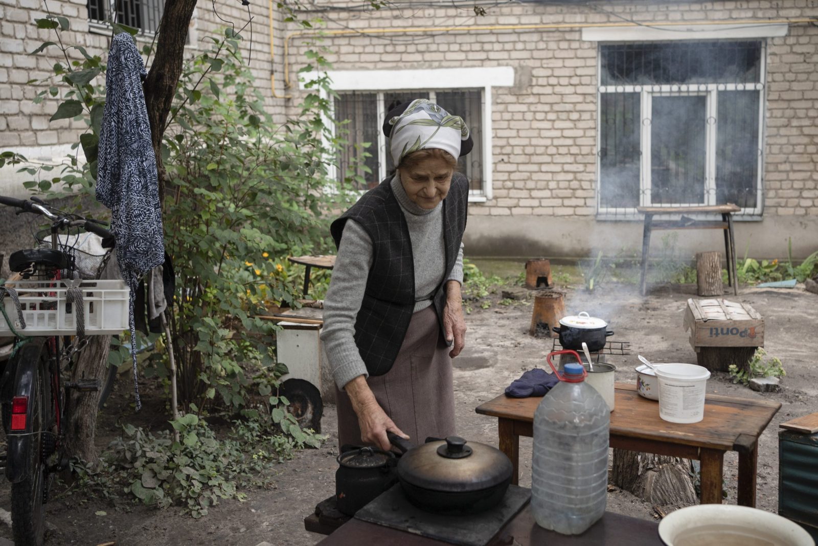 epa10188671 Maria, 82, cooks food over an open fire as gas and electricity are not available, near a residential building in the recently recaptured city of Izyum, Kharkiv region, northeastern Ukraine, 16 September 2022, amid Russia's invasion. The Ukrainian army pushed Russian troops from occupied territory in the northeast of the country in a counterattack. Kharkiv and surrounding areas have been the target of heavy shelling since February 2022, when Russian troops entered Ukraine starting a conflict that has provoked destruction and a humanitarian crisis.  EPA/ANASTASIA VLASOVA