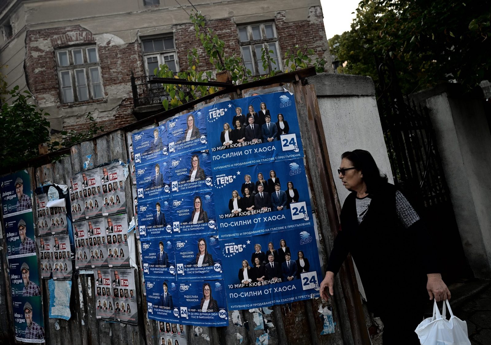 epa10213201 A woman walks past election posters in Dupnica, Bulgaria, 29 September 2022. The 2022 Bulgarian parliamentary election is scheduled for 02 November.  EPA/VASSIL DONEV