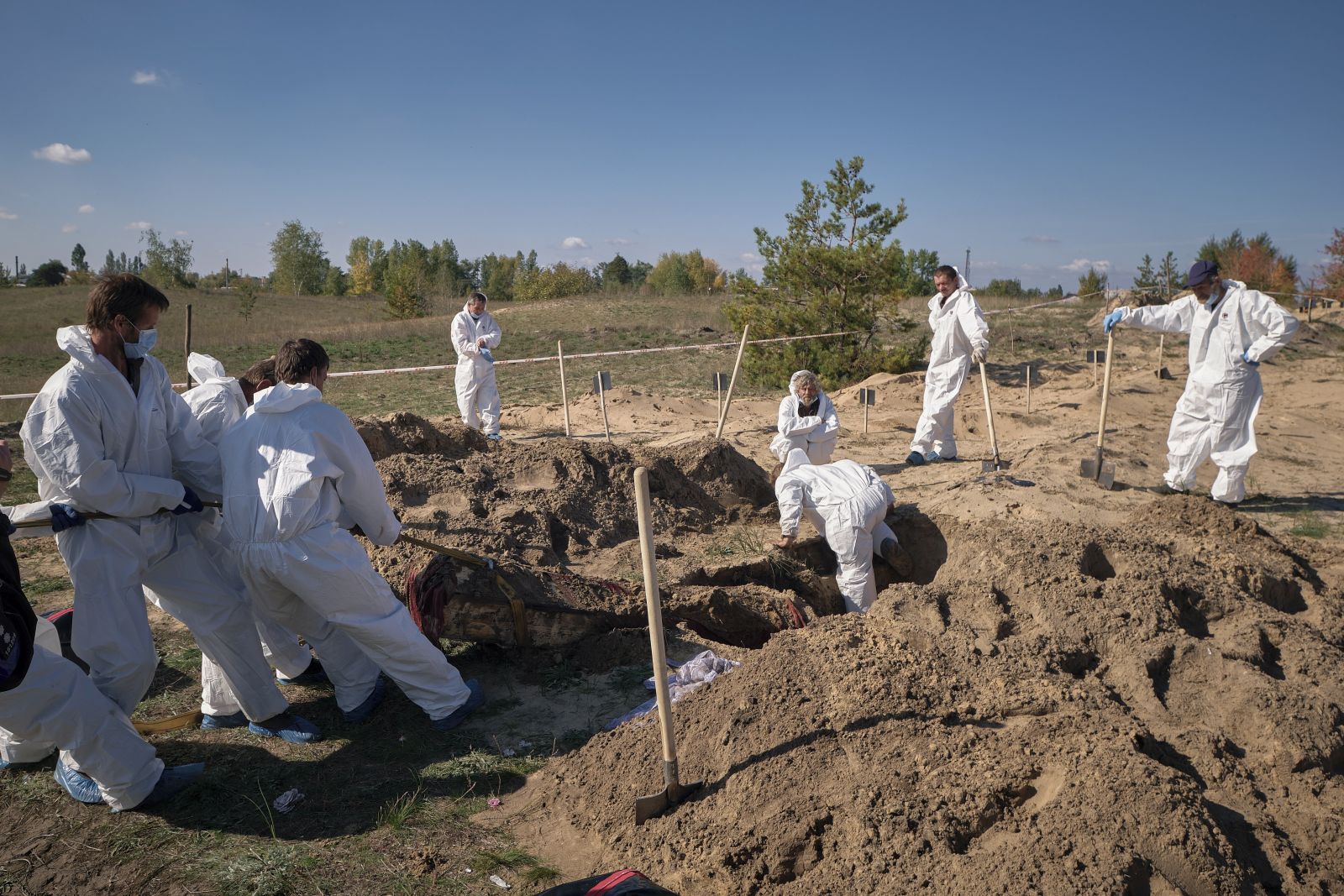 epa10229372 Forensic technicians work at a burial site near the recently recaptured city of Lyman, Donetsk area, Ukraine, 07 October 2022. A burial site with more than 50 graves was found after Ukrainian troops recaptured the town of Lyman. Ukrainian authorities have started exhuming and indentifying the bodies of the partially unmarked graves. Russian troops entered Ukraine territory on 24 February 2022, starting a conflict that has provoked destruction and a humanitarian crisis.  EPA/YEVGEN HONCHARENKO