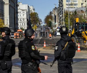 epaselect epa10234457 Armed police officers guard the area as municipal service workers (back) conduct repair works on a road after shelling in downtown Kyiv (Kiev), Ukraine, 10 October 2022. Explosions have been reported in several districts of the Ukrainian capital Kyiv on 10 October. At least 11 people died and dozens injured as a result of rocket attacks, the State Emergency Service (SES) of Ukraine said. Russian troops entered Ukraine on 24 February 2022 starting a conflict that has provoked destruction and a humanitarian crisis.  EPA/OLEG PETRASYUK