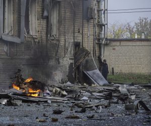epa10264094 A Russian policeman (C, rear) stands at the site of a car explosion near the 'ZaTV' broadcaster building in Melitopol, Zaporizhzhia region, southeastern Ukraine, 25 October 2022. At least five people were injured after a car exploded near the building of the 'ZaTV' television company in the city of Melitopol, said journalist Alexander Malkevich, a member of the Russian Public Chamber who oversees the work of the television company.  EPA/STRINGER