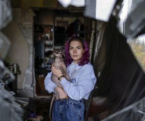 epa10271556 Katja, 23, holds her cat Donald as she poses for a photo taken through the shattered window of her old apartment in Zaporizhzhia, Ukraine, 28 October 2022. The flat where she used to live with 19 cats and other animals, was hit during a Russian missile strike the previous month. She has since moved to a new apartment in the city. Russian troops on 24 February entered Ukrainian territory, starting a conflict that has provoked destruction and a humanitarian crisis.  EPA/HANNIBAL HANSCHKE